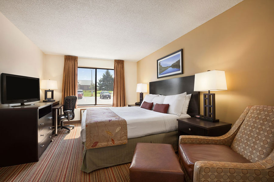 executive king room with arm chair, TV, dresser, and mini fridge at Ramada by Wyndham Wisconsin Dells