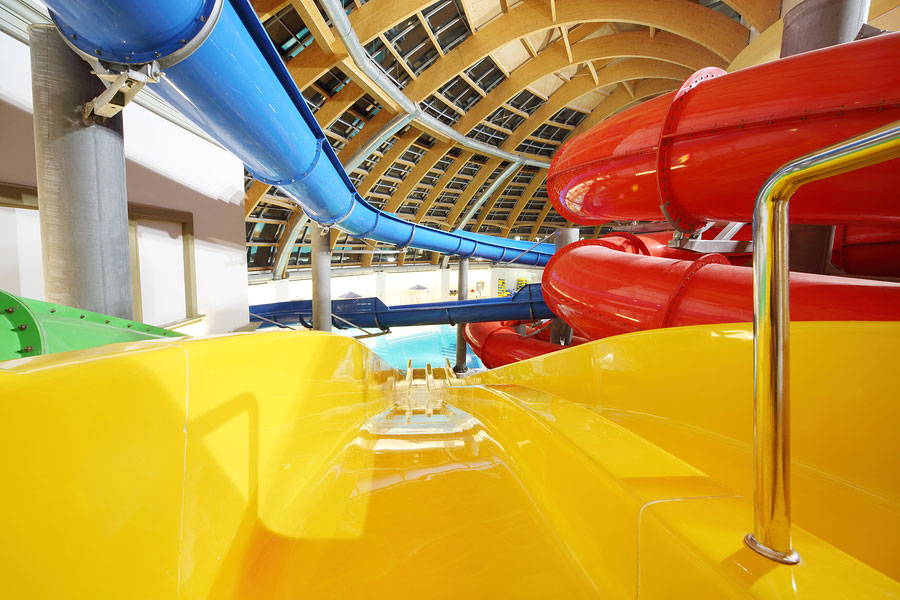 Big multi-colored indoor water slides in aquapark. Descent yellow slide.