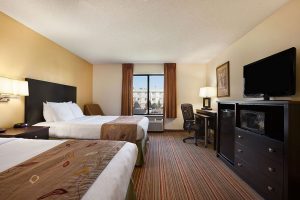 Standard queen bed room across from TV, dresser, mini fridge and work desk with chair at Ramada by Wyndham Wisconsin Dells