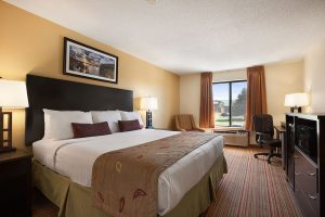 standard king room with bed across from dresser with microwave at Ramada by Wyndham Wisconsin Dells