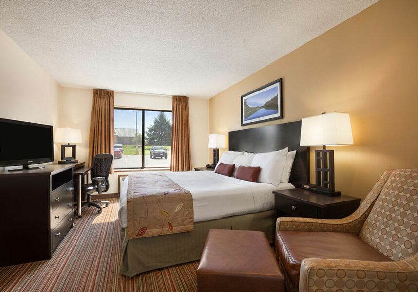 executive king room with arm chair, TV, dresser, and mini fridge at Ramada by Wyndham Wisconsin Dells